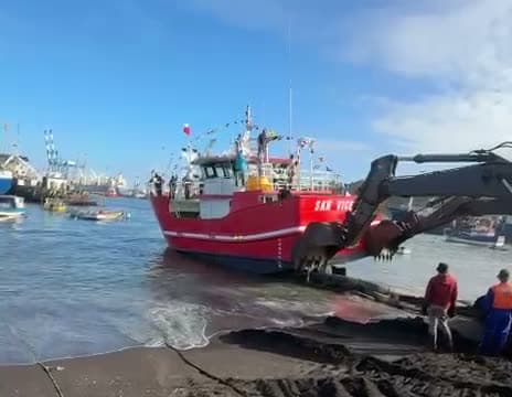 Botadura de la embarcación pesquera SAN VICENTE en Talcahuano, empujada por una retroexcavadora hacia el agua